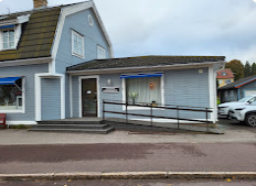 Blått hus med ramp och fönster, beläget vid en gata med parkerade bilar.