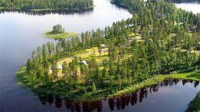 En vy över en sjö med omgivande skog och öar, med hus synliga på land.