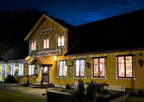 En gul gästgivergård med stora fönster, belägen i natten med belysning som framhäver byggnadens detaljer.