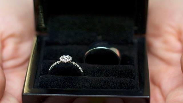 Två ringar i en svart smyckesask med mjukt foder, en med diamant och en enkel bandring.
