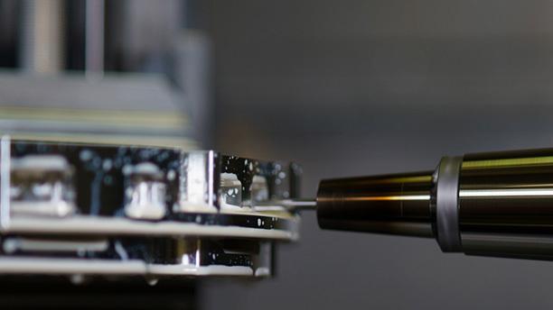 Närbild av en precisionsmaskin med en metallfräs som bearbetar en detalj.