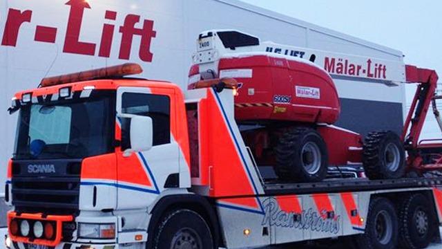 En lastbil med en röd lift på flaket, med en stor logotyp för "Målar-Lift" i bakgrunden.