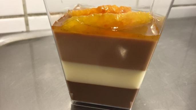 En dessert i ett glas med tre lager: choklad, vit choklad och apelsinmarmelad på toppen.