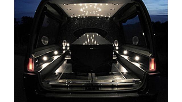 En svart kista i en limousine med stämningsfull belysning och en elegant interiör.