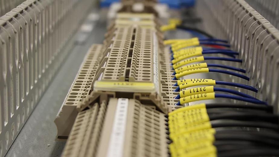 En närbild av en kabelkanal med färgkodade kablar och anslutningar i en elektrisk panel.