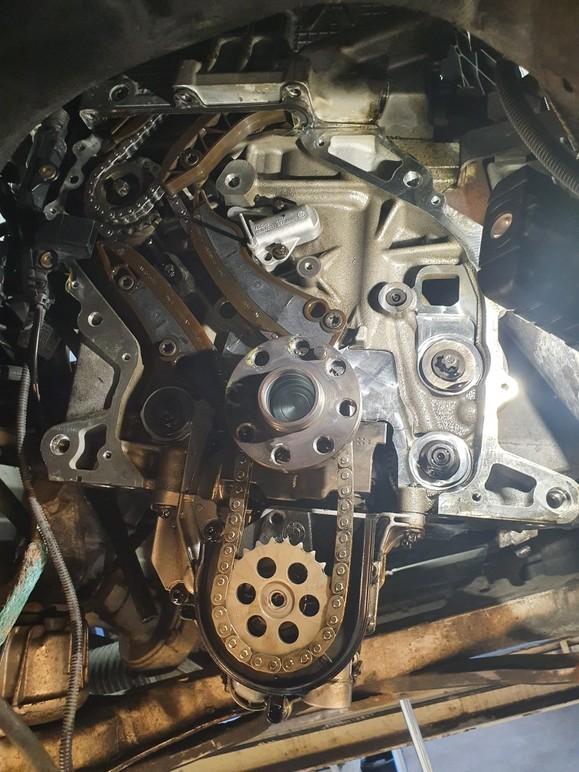 Detaljbild av en motor med synliga kedjor, drev och mekaniska komponenter i en bil.