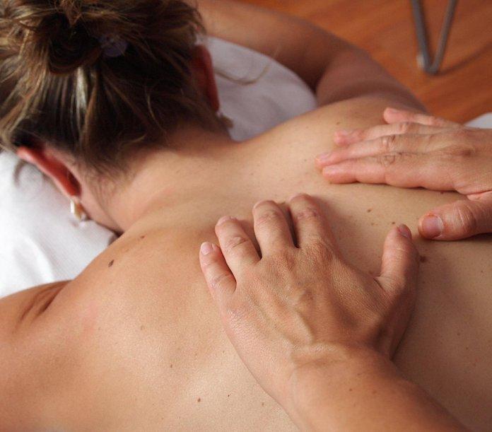 En person får en avslappnande massage på ryggen av en massör i en lugn miljö.