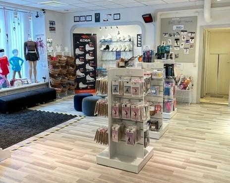 Butik med kläder och skor, hyllor med accessoarer och en sittgrupp i en modern inredning.