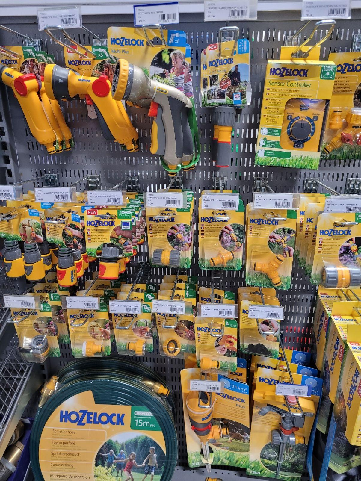 En hylla med Hozelock trädgårdsverktyg, inklusive sprutor, kopplingar och slangar, i en butik.