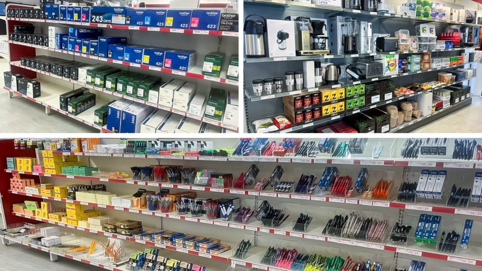 Hylla med kontorsmaterial, inklusive bläckpatroner, kaffemaskiner och skrivverktyg i en butik.